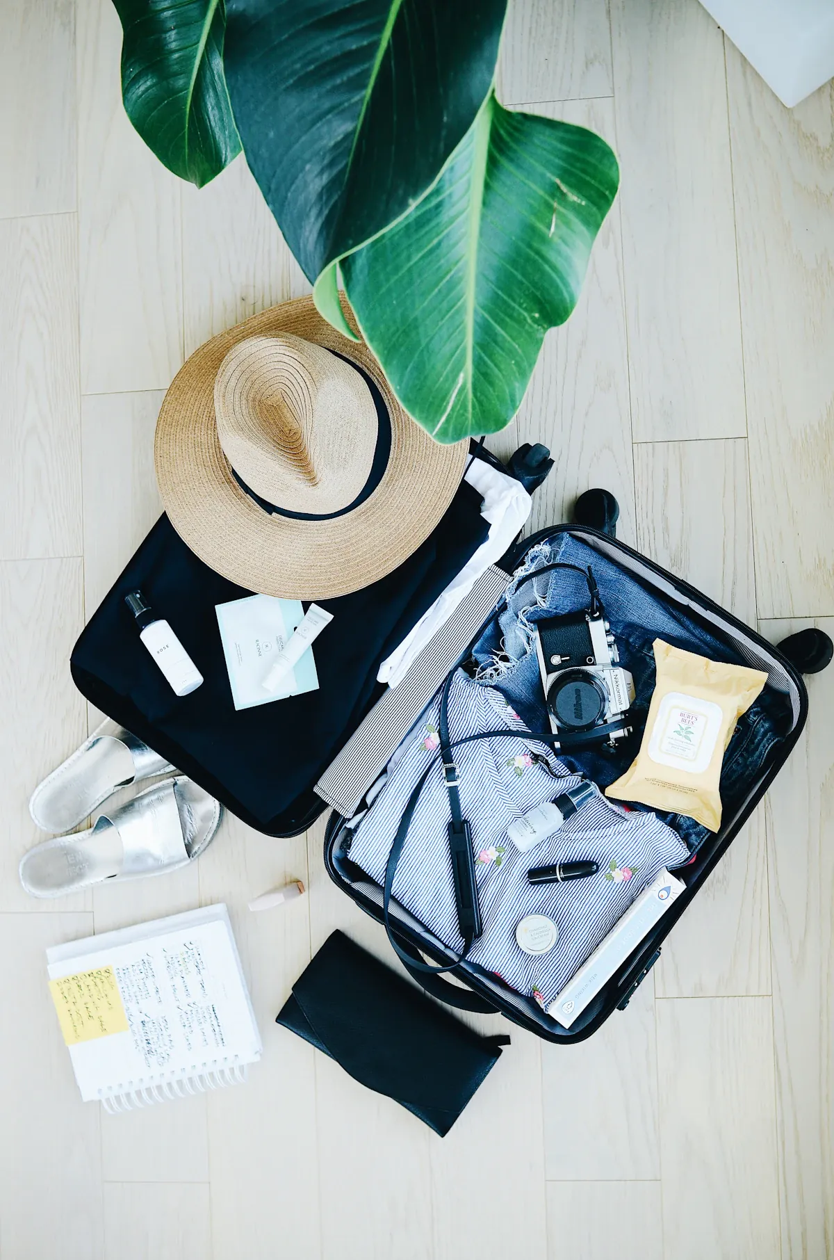 An open suitcase with travel essentials and a hat