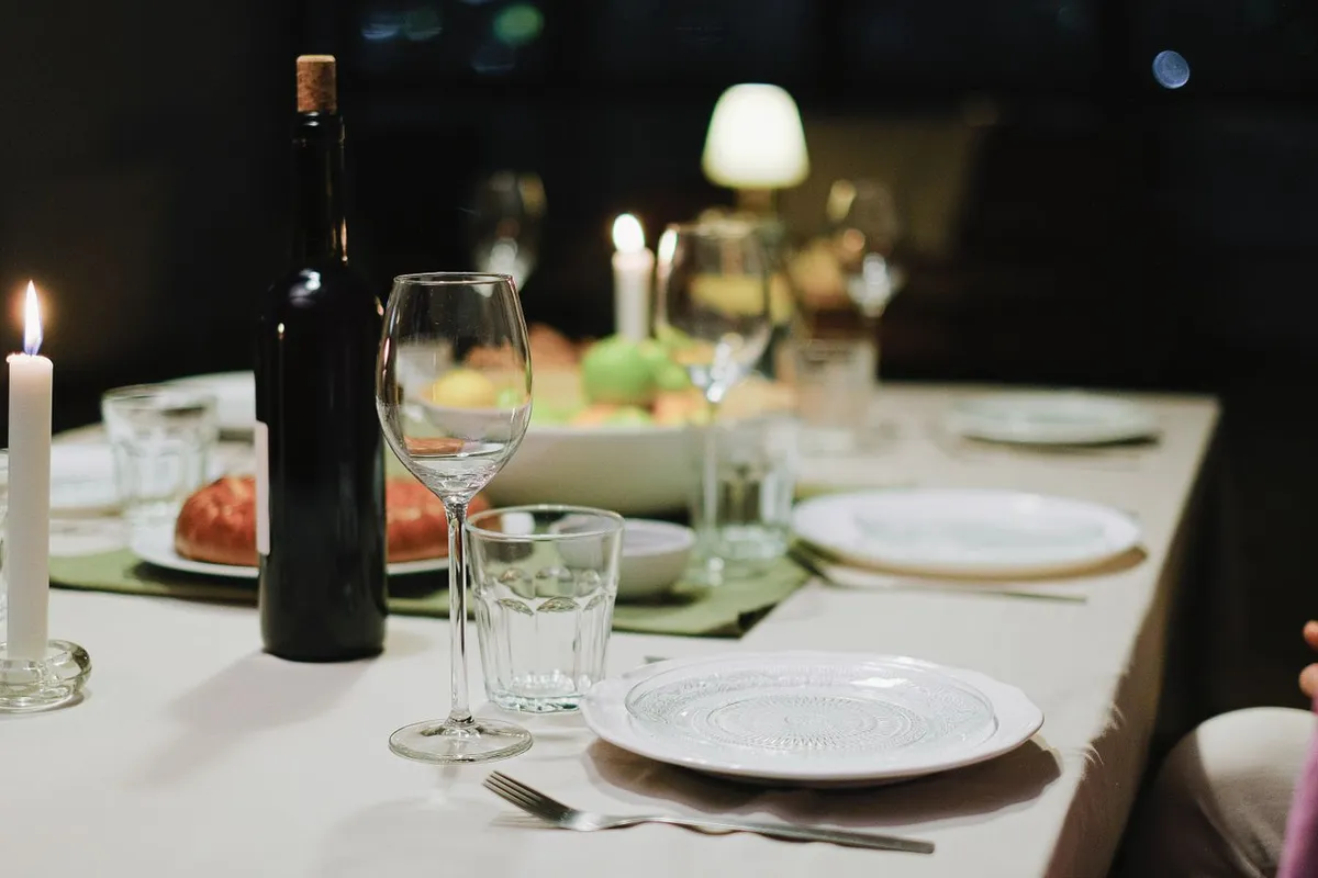 A restaurant dinner table set with plates, wine glasses and candles.